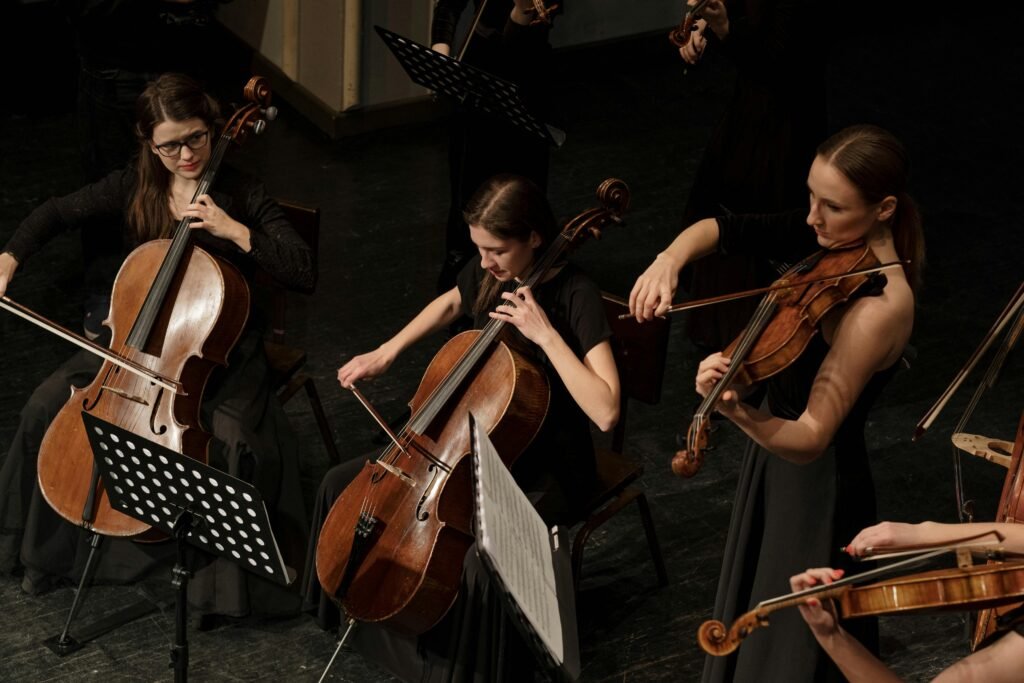 Women musicians playing cellos and violins in an orchestra performance.